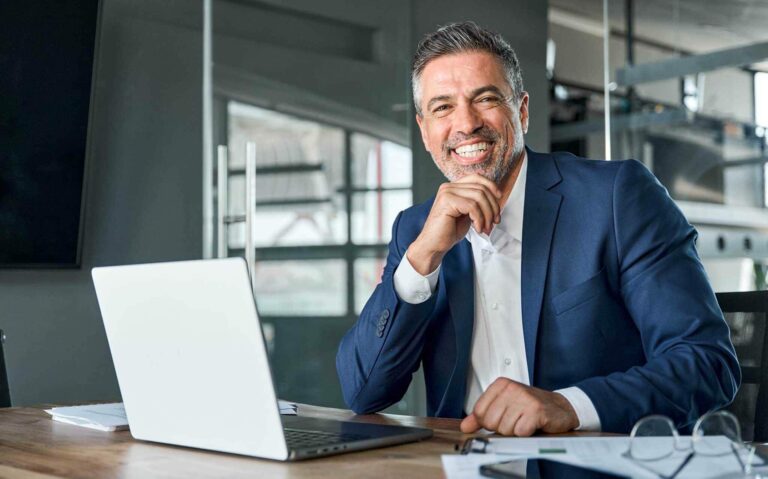 man sitting in his desk and smiling - insurance broker vs insurance agent Harvey Insurance