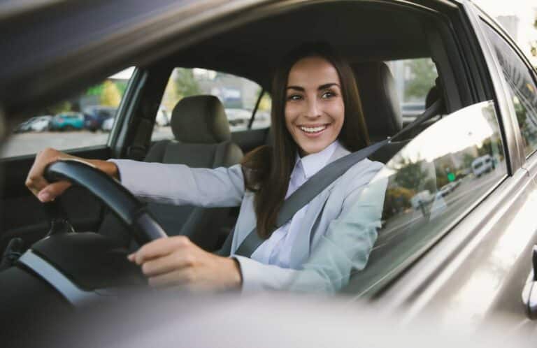 woman inside her car smiling about auto insurance quotes Harvey Insurance